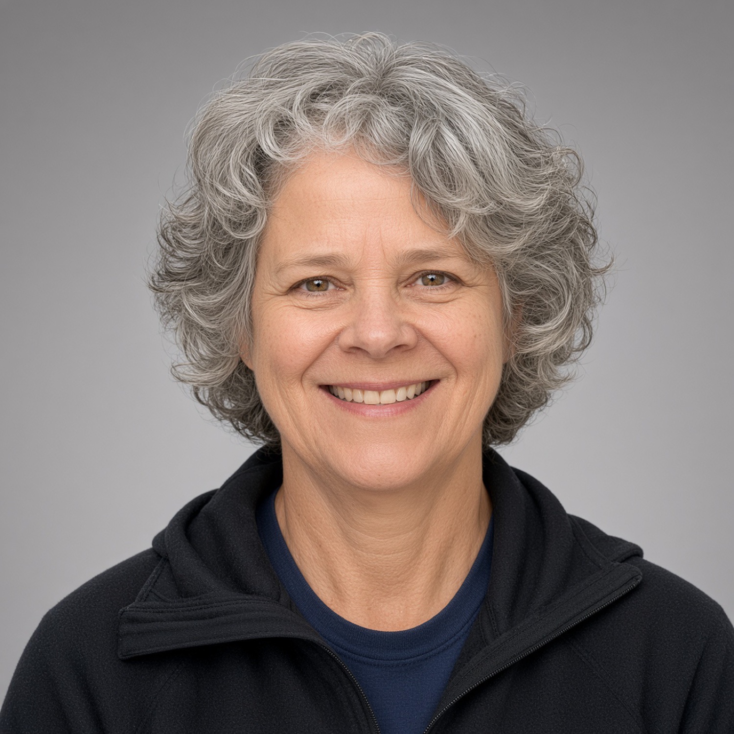 Christine Mackey smiling, with curly hair and a fleece jacket